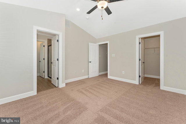 unfurnished bedroom featuring a spacious closet, lofted ceiling, light carpet, a closet, and ceiling fan