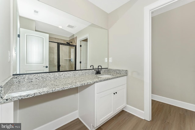 bathroom with hardwood / wood-style flooring, vanity, and an enclosed shower