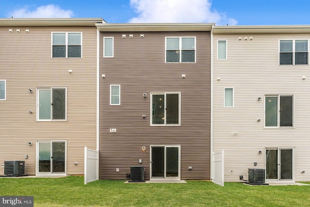 rear view of property with a lawn and central air condition unit