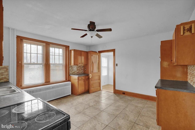 kitchen with radiator, electric range oven, plenty of natural light, and backsplash