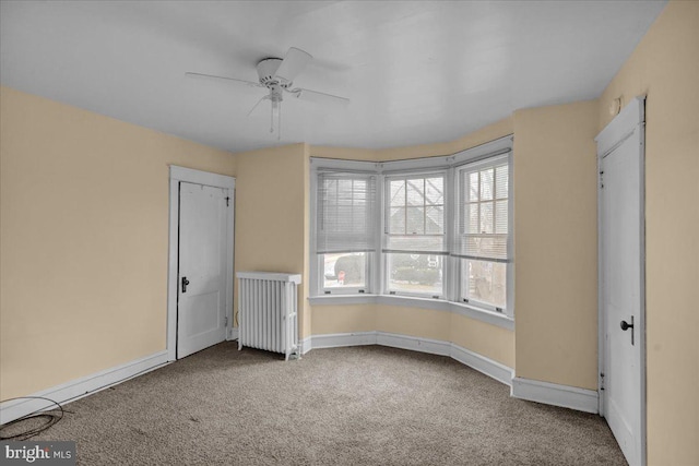 unfurnished bedroom featuring ceiling fan, radiator, and carpet floors