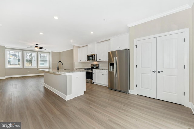 kitchen with ceiling fan, a kitchen island with sink, appliances with stainless steel finishes, and white cabinetry