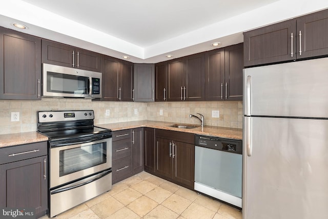 kitchen featuring light stone countertops, appliances with stainless steel finishes, sink, backsplash, and dark brown cabinets