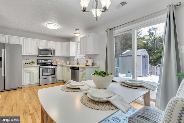 kitchen with white cabinets, a textured ceiling, appliances with stainless steel finishes, and plenty of natural light