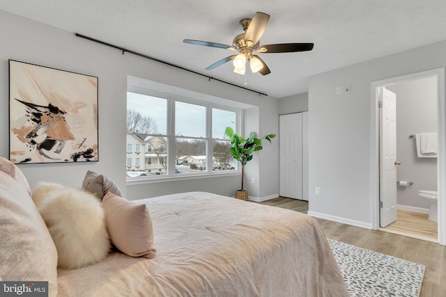 bedroom with ensuite bathroom, ceiling fan, light wood-type flooring, a closet, and a textured ceiling