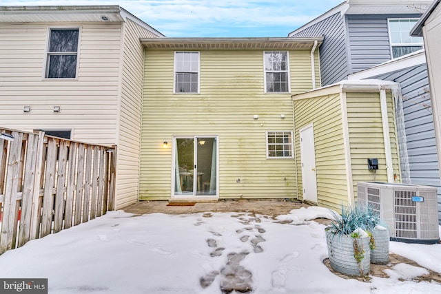 snow covered back of property featuring central AC