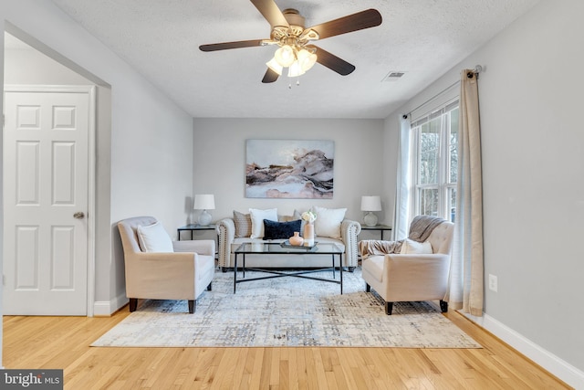 living area featuring a textured ceiling, ceiling fan, and hardwood / wood-style flooring