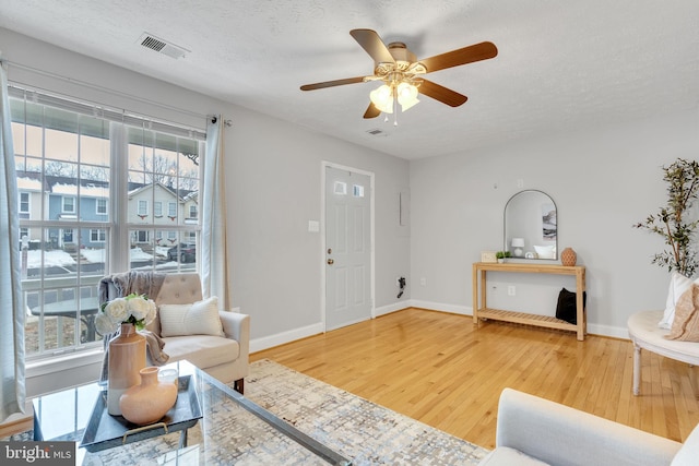 living room featuring ceiling fan, wood-type flooring, and a textured ceiling