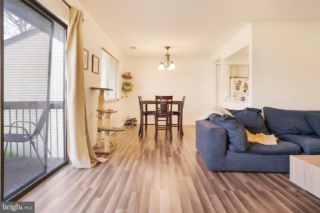 living room with wood-type flooring, an inviting chandelier, and ornamental molding