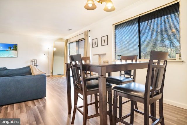 dining space featuring wood-type flooring, a wealth of natural light, and crown molding