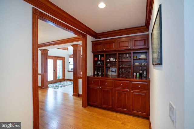 bar featuring ornate columns, ornamental molding, french doors, and light wood-type flooring