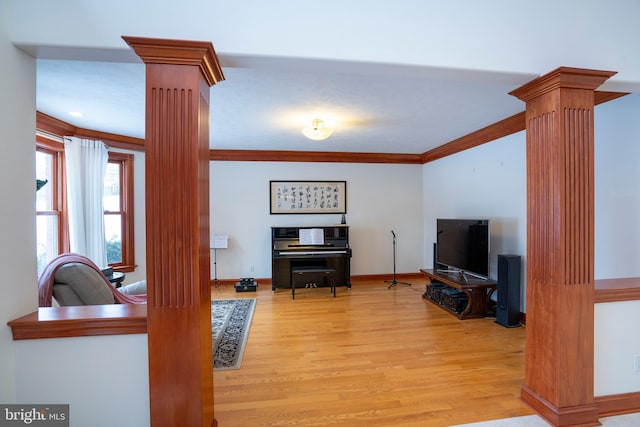 living room with light wood-type flooring, ornamental molding, and decorative columns