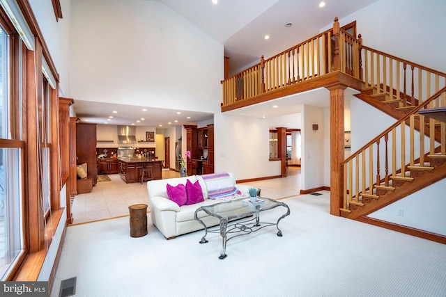 living room featuring light carpet, a towering ceiling, and decorative columns