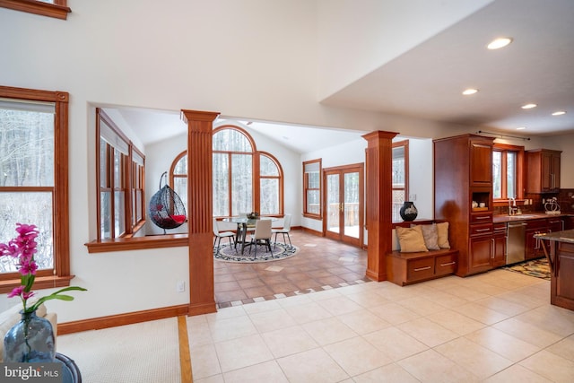 foyer with sink, light tile patterned flooring, lofted ceiling, and decorative columns