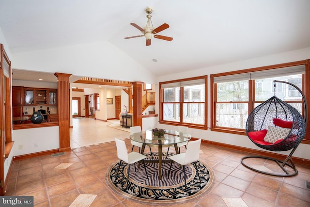 tiled dining space with high vaulted ceiling, ceiling fan, and ornate columns