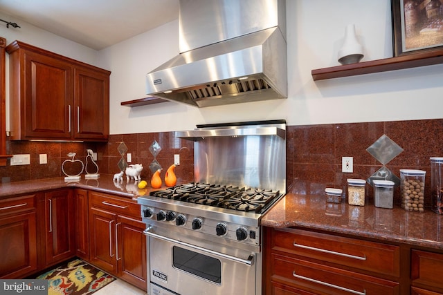 kitchen with premium range, dark stone counters, exhaust hood, and tasteful backsplash