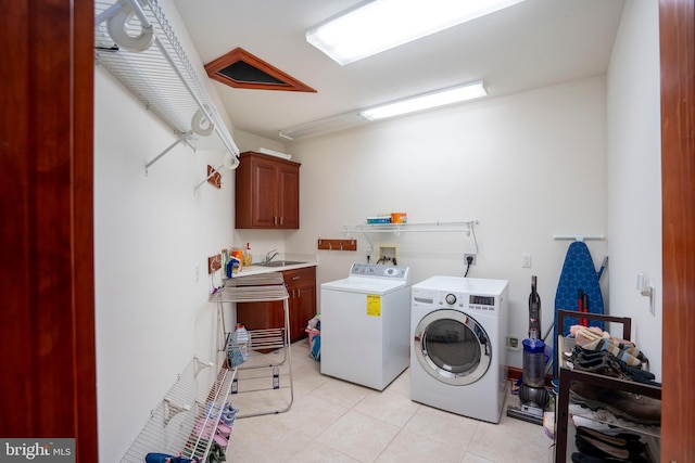 washroom with light tile patterned floors, sink, independent washer and dryer, and cabinets