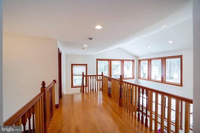 corridor featuring a wealth of natural light, lofted ceiling, and light hardwood / wood-style floors