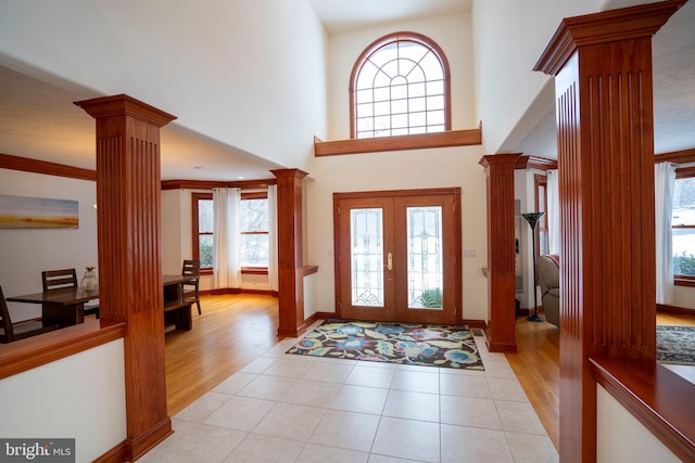 tiled foyer featuring a towering ceiling, french doors, and decorative columns