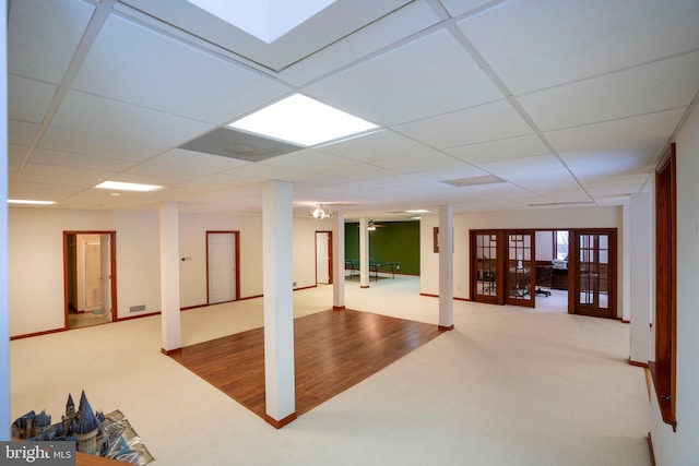 basement with carpet, a drop ceiling, and french doors