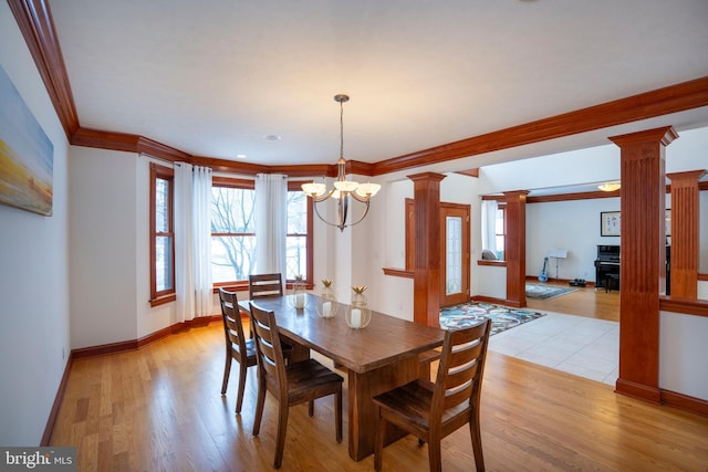 dining area featuring light hardwood / wood-style flooring, a notable chandelier, crown molding, and decorative columns