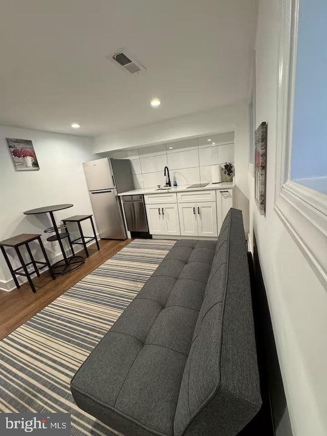 bar featuring visible vents, dark wood finished floors, freestanding refrigerator, stainless steel dishwasher, and a sink