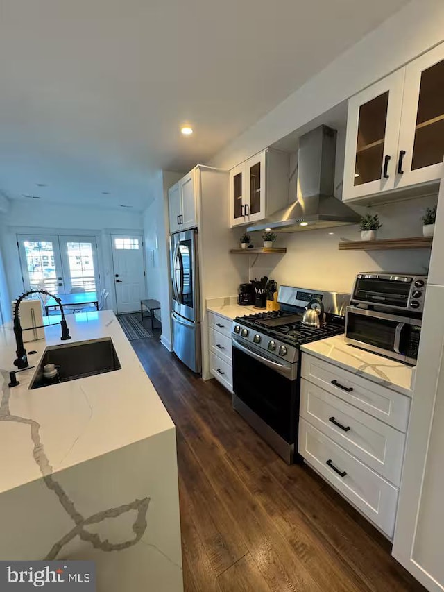 kitchen featuring white cabinets, appliances with stainless steel finishes, glass insert cabinets, extractor fan, and a sink