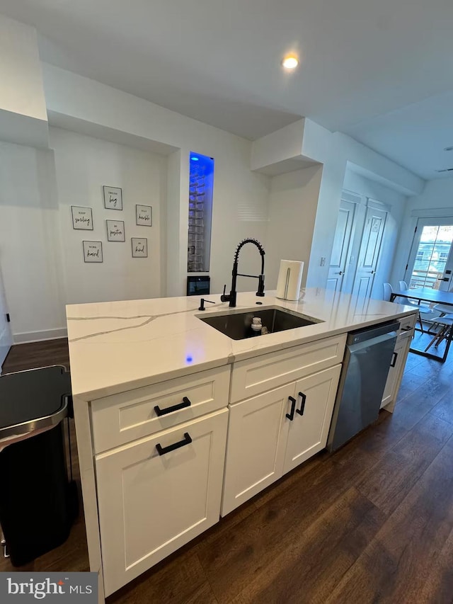 kitchen featuring light stone counters, dark wood-style flooring, a sink, white cabinetry, and stainless steel dishwasher