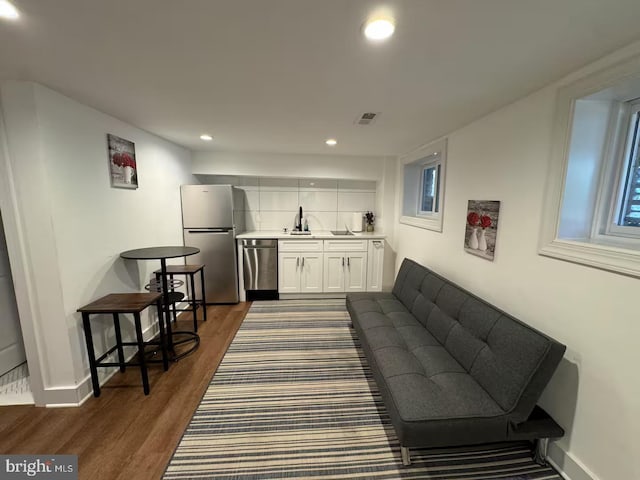 living area with recessed lighting, visible vents, baseboards, wet bar, and dark wood-style floors