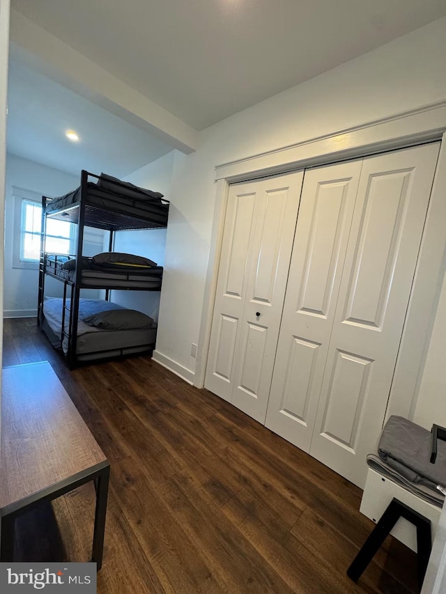 bedroom featuring baseboards, dark wood finished floors, and a closet