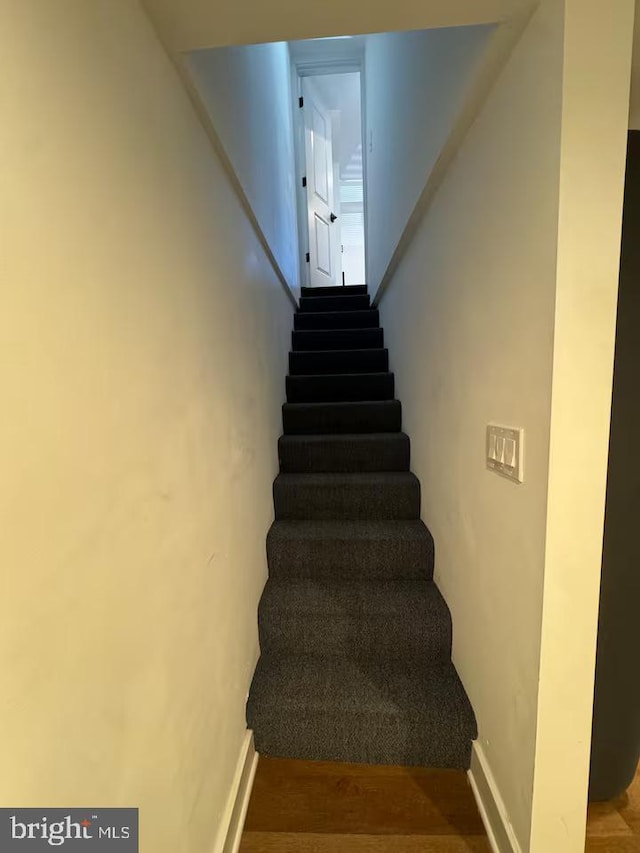 staircase featuring baseboards and wood finished floors