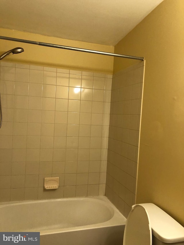 bathroom featuring tiled shower / bath and toilet