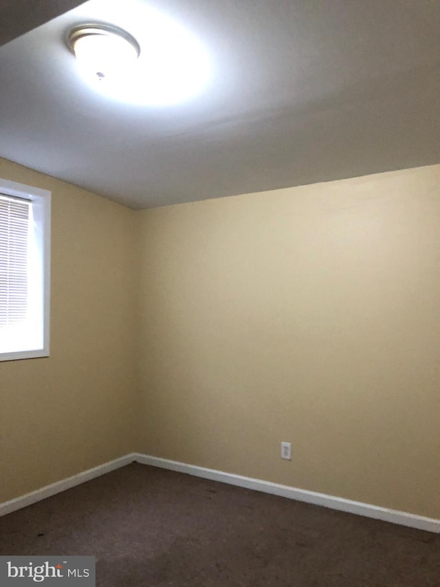 spare room featuring dark colored carpet