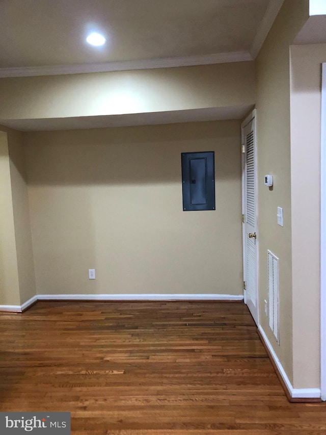 basement with dark wood-type flooring, crown molding, and electric panel