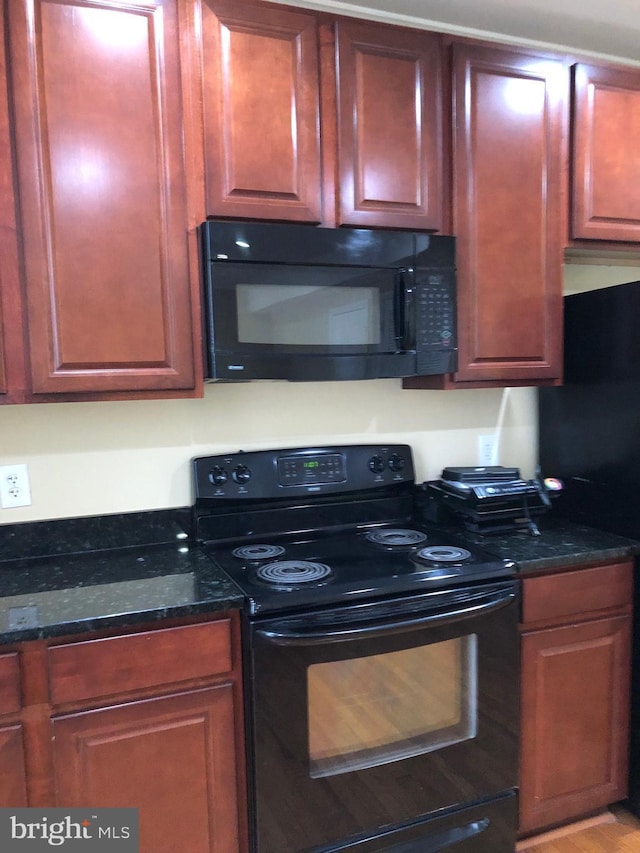 kitchen featuring dark stone counters and black appliances