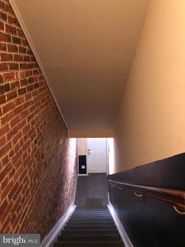 stairway featuring brick wall