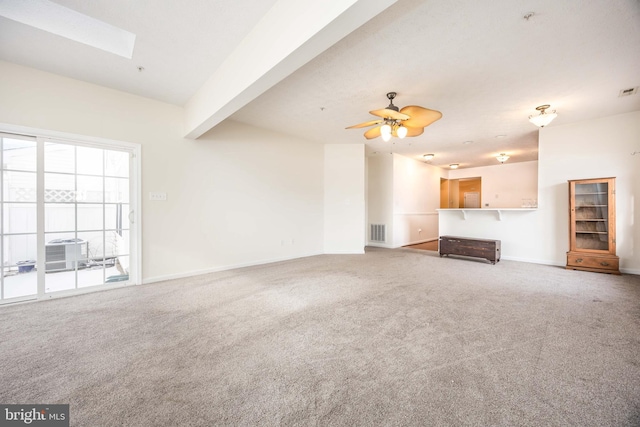 unfurnished living room with beamed ceiling, carpet floors, ceiling fan, and a skylight