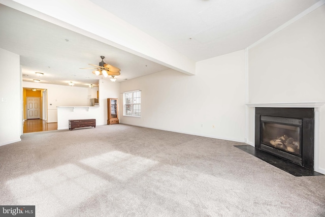 unfurnished living room featuring ceiling fan, carpet floors, and beamed ceiling