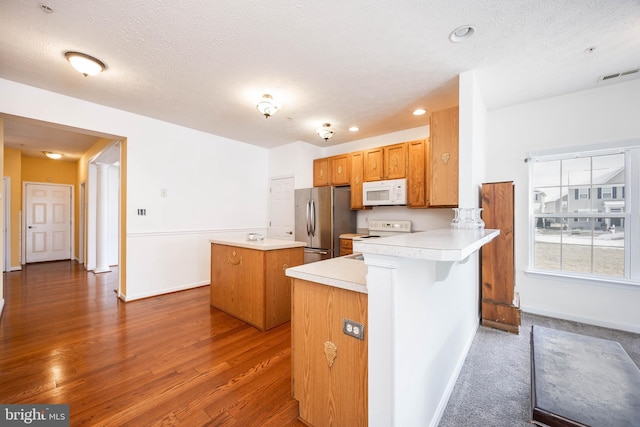 kitchen with stainless steel refrigerator, stove, dark hardwood / wood-style floors, a center island, and a textured ceiling