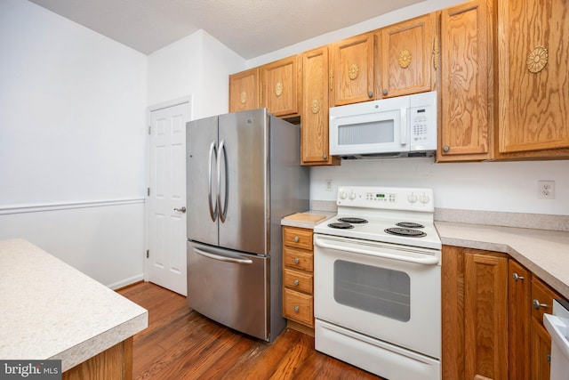 kitchen featuring white appliances and dark hardwood / wood-style floors