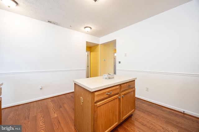 kitchen featuring hardwood / wood-style flooring, a center island, and a textured ceiling