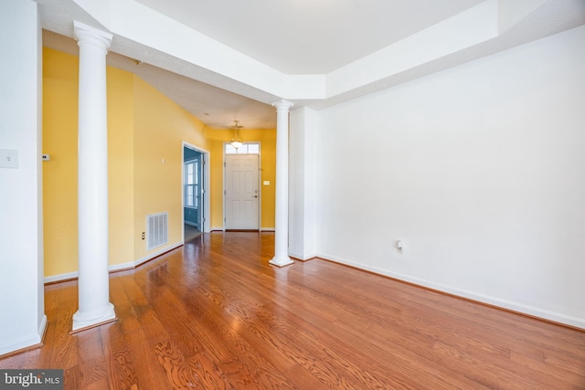 spare room featuring hardwood / wood-style floors and ornate columns