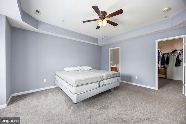 unfurnished bedroom with a closet, ceiling fan, a spacious closet, light colored carpet, and a raised ceiling