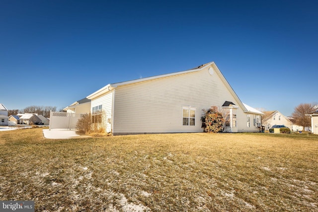 view of property exterior with a patio and a lawn