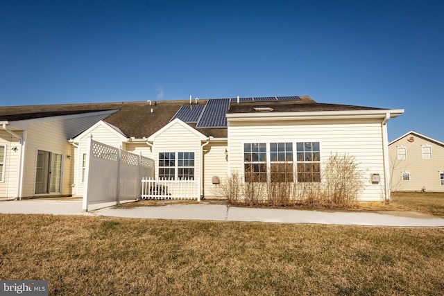 back of property with a yard and solar panels