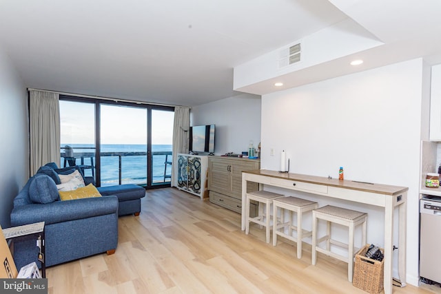 living room featuring a wall of windows and light hardwood / wood-style flooring