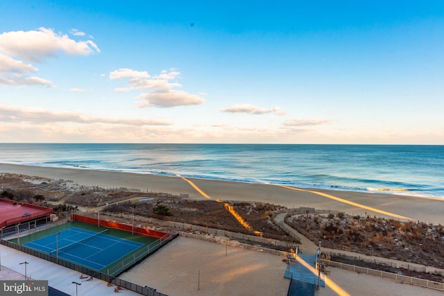 aerial view at dusk with a water view and a view of the beach