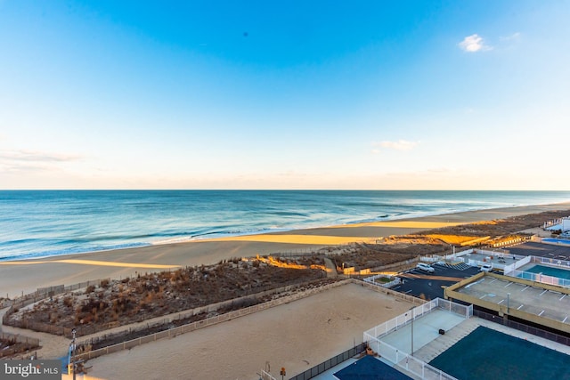 aerial view at dusk with a water view and a beach view