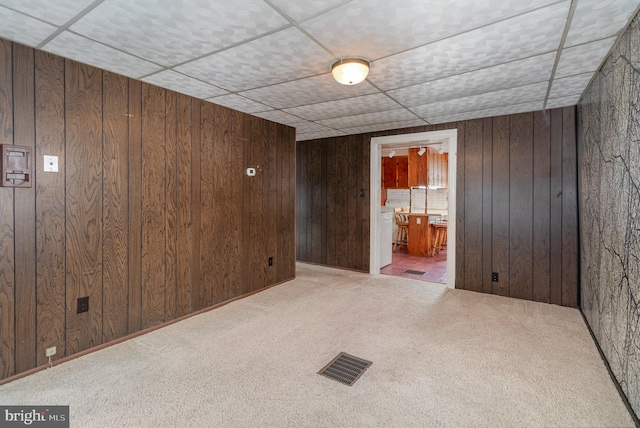 unfurnished room with light carpet and wood walls