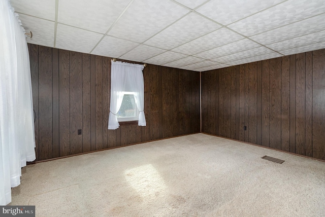 carpeted empty room featuring wooden walls